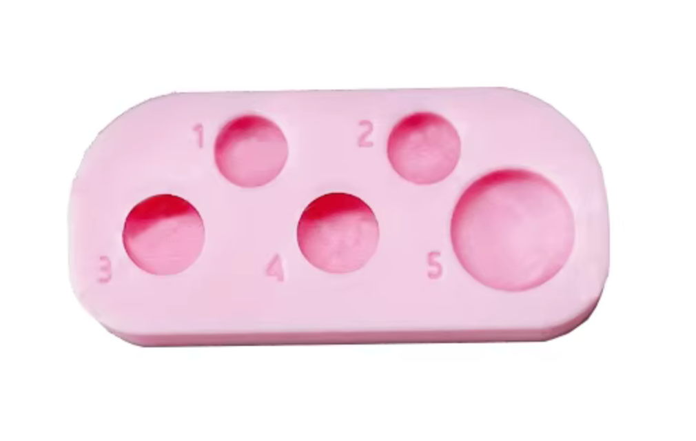 Pink silicone mold with circular cavities on a white background